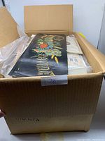 Photo of the open box showing papers and booklets inside with visible colored printed paper on top