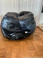 Photo of large black bean bag lounger on wooden floor, showing general shape and size.