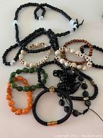Photo of a lot of 11 bracelets and 1 beaded necklace in various colors and materials showing beads and skull motifs