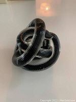 Black glass Celtic endless knot sculpture viewed from front showing intricate interwoven loops and glossy finish.