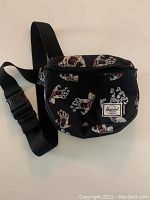 Front view of the black Herschel fanny bag decorated with Santa Cruz Screaming Hand print, adjustable strap visible.