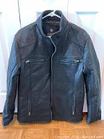 Front view of men's large black Buffalo jacket hanging on white hanger showing zippered front and pockets.