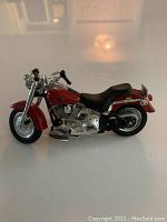 Side view of the red and silver miniature Harley Davidson motorcycle model showing detailed engine and black seat.