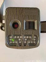 Front view of Moultrie GameSpy 2 game camera showing camouflaged textured casing, camera lens, and infrared LED array.