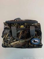 Front view of the Plano camouflage lunch bag with patch and carrying handles