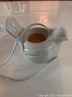 Side view of white bird ceramic wax warmer with amber wax inside and white power cord