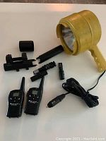 Photo showing all items including two walkie talkies, yellow spotlight, animal calls, and scope mount laid out together.