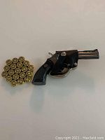 Front view of black revolver-shaped lighter with bullets arranged in a circle