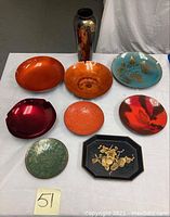 Overview photo showing entire lot of enamel bowls, tole tray, and vase arranged on table.