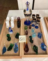 Full view of set on wooden trays including crystal decanter with stopper, 5 sherry glasses, and 15 art glass figurines in various colors and shapes.