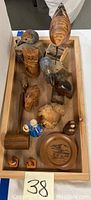 Top view of the assortment of wooden and ceramic figurines on a wooden tray showing birds, a carved face, and small ceramic pieces.