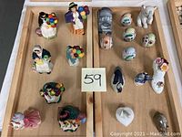 Overview of multiple porcelain figurines and ornamental eggs arranged on wooden trays, showing all items included in the lot