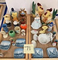 Overview of collectible trinkets and figurines arranged on wooden trays showing a variety of ceramic small objects, plates, and figurines.