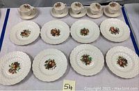 Photo of full set displaying 6 saucers, 6 cups, and 2 dinner plates with fruit motif and textured white background