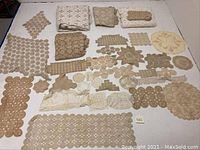 Overview of all doilies and tablecloths laid out on a white background showing varied sizes and shapes in beige and brown tones.
