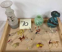 Photo showing collection of glass animal figurines and vases on a wooden tray with a note marked 70.