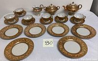 Full tea set laid out showing cups, saucers, bread plates, teapot, sugar bowl with lid, and creamer.