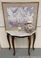 Marble top end table with floral vase and framed watercolor painting behind it
