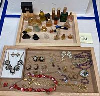Image showing two wooden trays with assorted miniature perfume bottles on one and costume jewelry on the other.