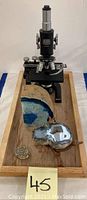 Black metal Spencer Buffalo U.S.A. microscope with two sliced geodes and small geode cluster on wooden tray