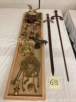 Overview of all items on wooden trays showing swords and various brass decor items.
