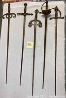 Five decorative sword skewers laid out on white cloth, overhead view