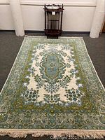 Wide view of Kashmir rug on floor with wooden washstand behind it