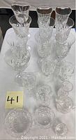 Full set of various crystal stem glasses, a creamer, sugar bowl, and vase arranged on a table