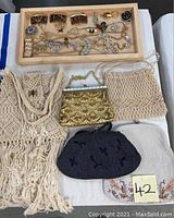 Top view of assorted costume jewelry including hair combs, brooches, rings, necklaces laid in wooden tray; five women's evening purses arranged below on white surface