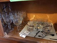 Shelved assortment of clear glass water goblets and shot glasses on a tray