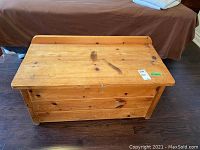 View of chest's top showing wood grain, discoloration spots, and lock hardware on front center.