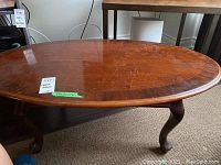 Photo of oval wooden coffee table top showing scratches and general wear.