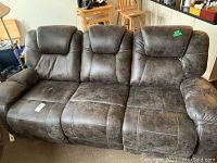 Front view of dark brown fabric leather imitation upholstered couch with three seats and reclining feature on both ends