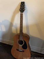 Full view of the 6-string Varitek acoustic guitar showing natural wood finish and black pickguard.