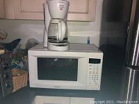 White Samsung microwave on kitchen countertop with digital keypad and display