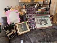 View showing three framed prints and two mirrors arranged on a couch in a living space with kitchen in background.