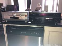 Two AV receivers placed on a shelf above a dishwasher. Panasonic SA-HT400 on the left, Pioneer VSX-516 on the right.