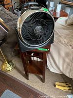 Honeywell portable fan positioned on top of the wooden stand, showing fan front and part of stand and surroundings.
