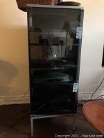 Front view of the stereo cabinet showing glass doors and shelving inside.