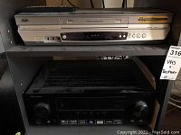 Black Pioneer A/V receiver on lower shelf with front display, control knobs and buttons, cables visible behind.