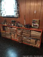 Bookshelf filled with magazines and decorated with model cars and figurines on top, showing front view.