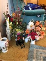 Wide shot showing various faux flowers in different containers including miniature cart and ceramic vases, white ginger jar, and white ceramic cat figurine.