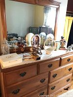 Wide view showing dresser with mirror and assorted items including figurines, plates, glass clock, and ceramic basket.