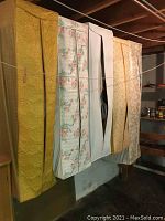 Four garment bags hanging, each containing multiple men’s clothing items.