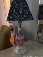 Front view of one porcelain table lamp with woman figure base and floral shade