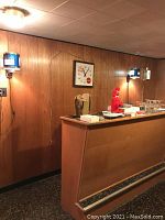Overview of basement bar showing two Hamms Beer rotating lights on either side of Coca-Cola clock and barware on counter
