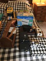 Photo showing the shoeshine kit, Remington shaver, bathroom scales, shredder in box, and other smaller items on a bed.