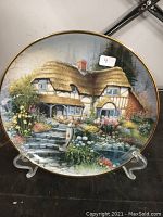 Front view of the collector plate depicting a country cottage with vibrant garden scenery in fine detail.
