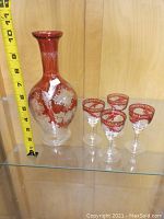Image of the red and white antique glass decanter showing approximate height with tape measure