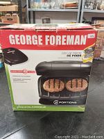 Front view of George Foreman Grill box showing grill image and branding.